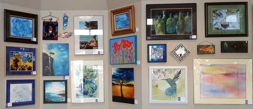 A collection of paintings hung on a wall at East Ludington Gallery