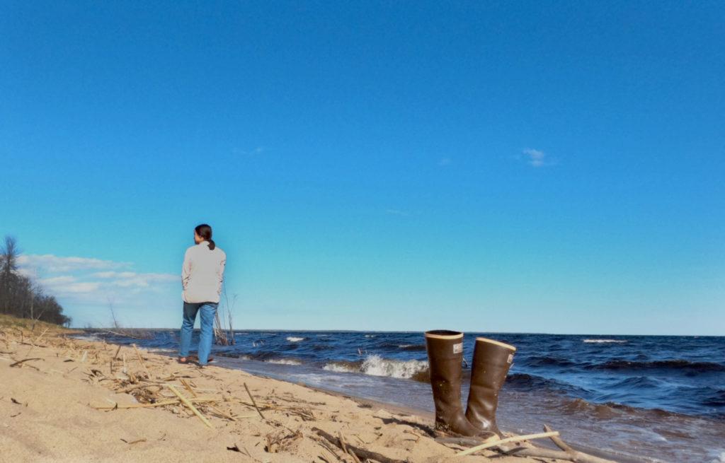 woman walking down the beach with boots in the foreground