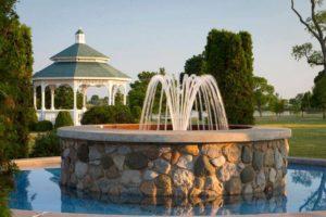 an outdoor fountain made of stone with a pavilion in the background