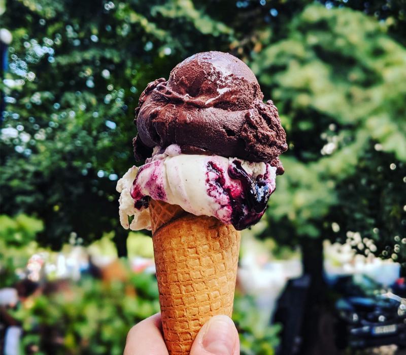 person holding ice cream cone in a park